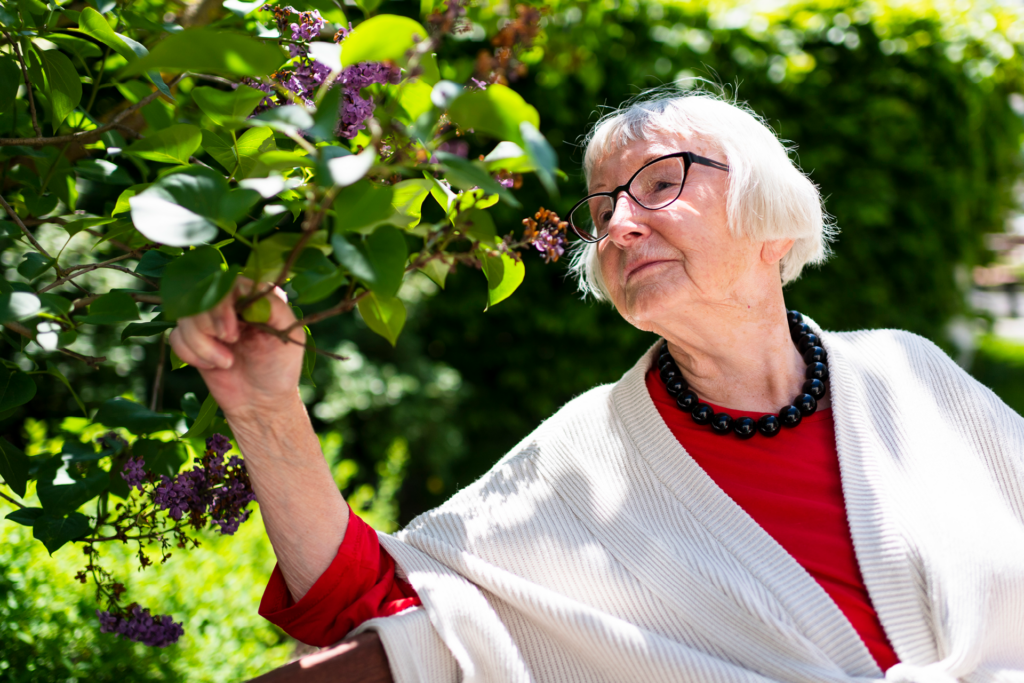Ältere Dame riecht entspannt an Blumen